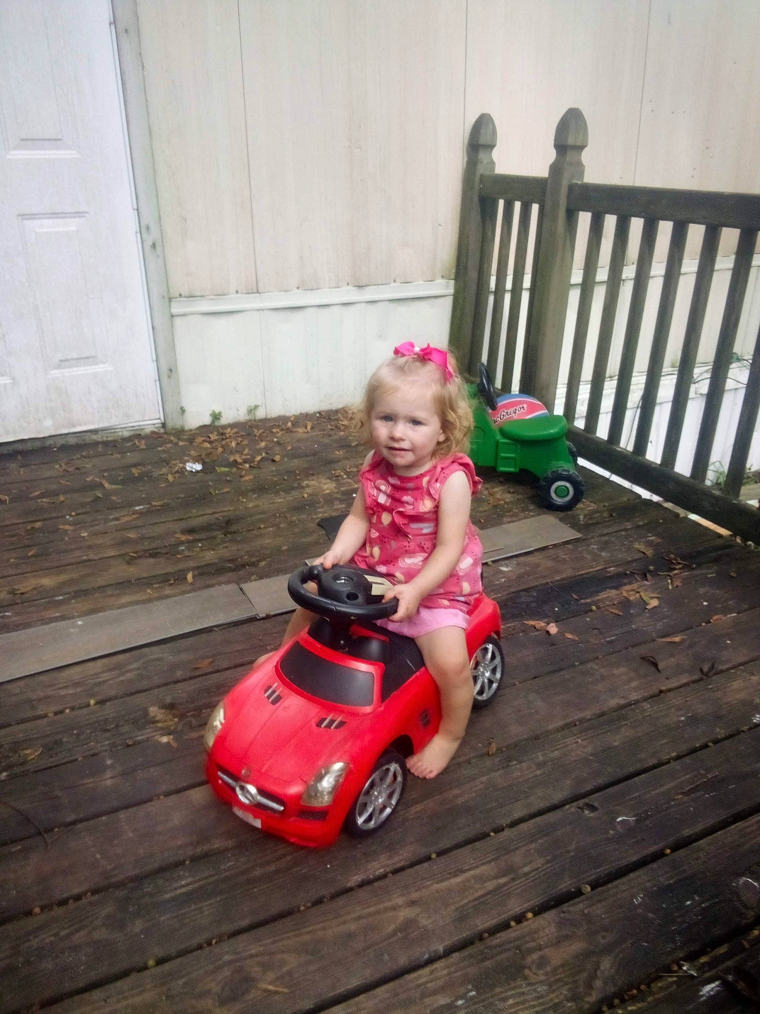 Avery is registered to the contest to win money with this photo: automotive_tire, baby, baby_toddler_clothing, child, door, dress, flooring, grass, happy, hardwood, magenta, motor_vehicle, person, riding_toy, smile, tire, toddler, toy, vehicle, wheel