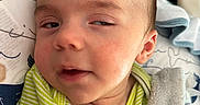 Judah joined the competition — help win amazing prizes! baby, infant, face, blanket, pillow, striped_clothing, hand, pacifier, sleepy, expression, closeup, skin, head, ear, soft_texture, child, indoors, resting, comfort, cute