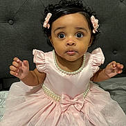 Alisha Roque joined the competition — help win amazing prizes! baby, bed, bow, child, curly_hair, flower_hair_clips, formal_wear, hands, indoors, jewelry, pearl_necklace, photography, pink_dress, portrait, ruffled_sleeves, sitting, smiling, tufted_backdrop, tulle_skirt, wide_eyes