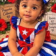 Alisha Roque is registered to the contest to win money with this photo: child, toddler, girl, portrait, smiling, curly_hair, bow, dress, patriotic, cuban, flag, red_white_blue, flowers, hibiscus, lantern, straw_hat, decorations, seated, indoors, festive