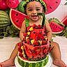 baby, child, smiling, happy, portrait, watermelon, fruit_cake, strawberries, blueberries, pineapple, fruit, costume, watermelon_hat, cucumber, birthday, celebration, sitting, indoor, colorful, food_photography