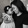 child, toddler, mother, parent, portrait, black_and_white, curly_hair, hair_bow, dress, pearls, smiling, affectionate, family, indoors, chandelier, elegant, sitting, holding, nose_to_nose, photography