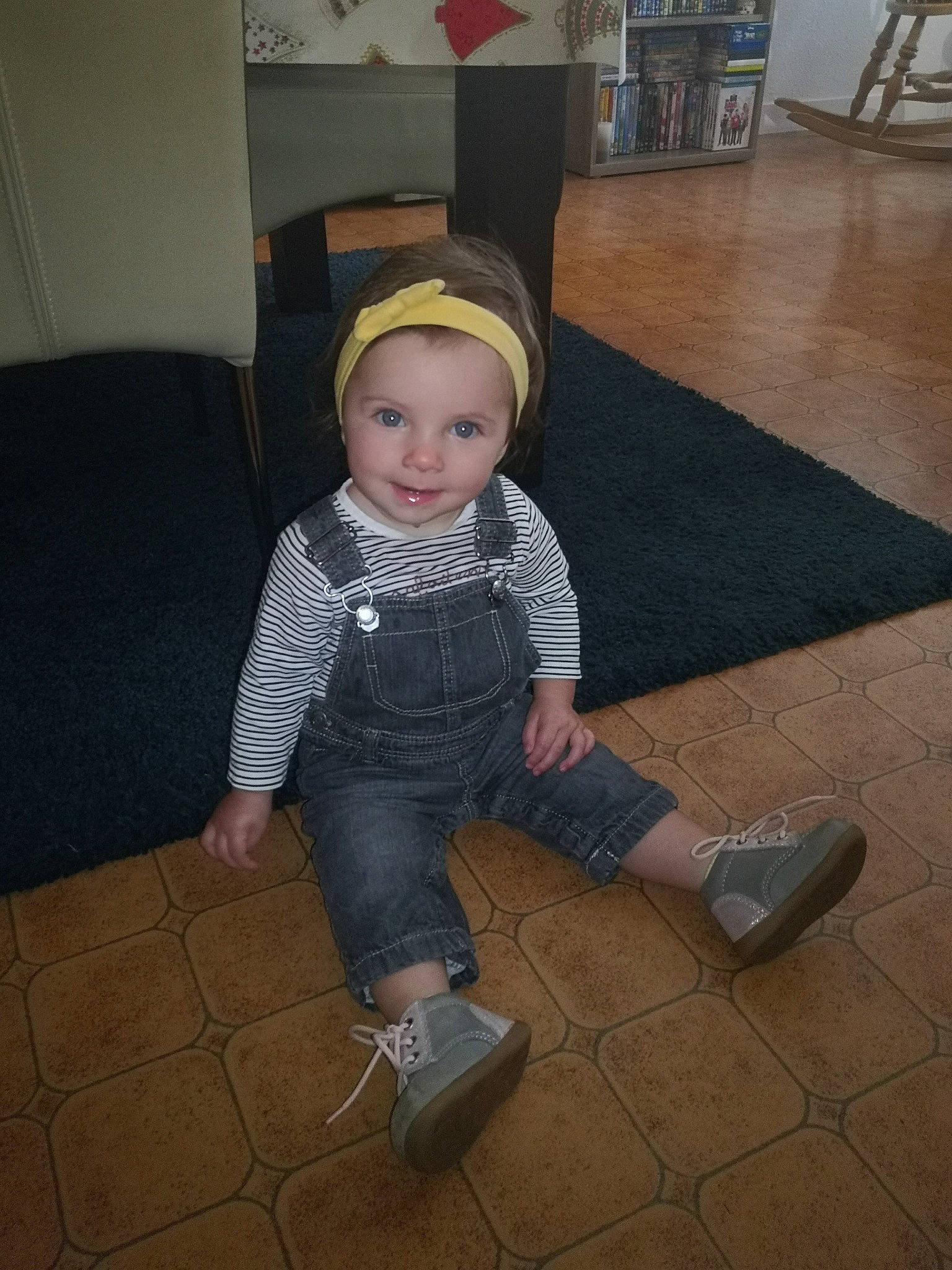 Mathilde participe au concours pour gagner de l'argent avec cette photo : baby, baby_toddler_clothing, cap, cheek, child, floor, flooring, fun, hardwood, hat, jeans, joy, person, road_surface, room, shoe, sitting, sleeve, smile, sneakers