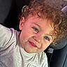 Araïk a rejoint le concours — aidez-le/la à gagner de superbes lots ! blue_eyes, car_seat, casual_clothing, child, closeup, curly_hair, cute, face, hair_accessory, happy, indoor, person, portrait, rosy_cheeks, seatbelt, skin, smile, toddler, white_shirt, young_child