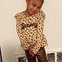 boots, brown_pants, child, clothing, cute, earrings, fashion, floor, girl, hair_bun, happy, indoor, leopard_print, long_sleeve, person, pose, smile, standing, wall, young