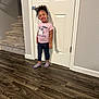 Miracle is registered to the contest to win money with this photo: child, toddler, smiling, standing, indoor, stairs, door, pink_shirt, unicorn, socks, wooden_floor, carpet, wall, happy, person, hair, clothing, footwear, home, portrait
