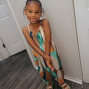 Legacy is registered to the contest to win money with this photo: child, girl, smiling, indoor, wall, floor, door, hair_bun, sandals, patterned_clothing, happy, standing, pose, young, fashion, person, cute, portrait, feet, accessories
