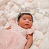 baby, infant, pink_dress, crown, headband, fluffy_cushions, soft_texture, newborn, portrait, cute, sleeping_area, indoor, adorable, child, celebration, soft_lighting, baby_girl, resting, closeup, cozy