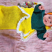 Meadow joined the competition — help win amazing prizes! baby, infant, blanket, knitted_blanket, headband, orange_headband, green_sweater, plush_toy, pink_blanket, soft_texture, lying_down, cute, small_hands, portrait, indoors, child, cozy, colorful, happy, face