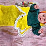 baby, infant, blanket, knitted_blanket, headband, orange_headband, green_sweater, plush_toy, pink_blanket, soft_texture, lying_down, cute, small_hands, portrait, indoors, child, cozy, colorful, happy, face