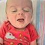 baby, car_print, child, close_up, cute, cute_outfit, eyes_closed, happy, indoors, infant, mouth_open, person, portrait, red_shirt, resting, smiling, soft_light, striped_blanket, tree_print, young