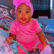 Mulani is registered to the contest to win money with this photo: baby, child, infant, pink_outfit, headband, bow, sitting, bedroom, bed, toy, smiling, portrait, indoors, colorful, fashion, baby_clothing, hands, feet, window, bedding
