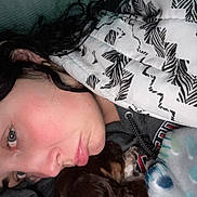 Gus Gus is registered to the contest to win money with this photo: person, dog, blanket, quilt, snuggling, cozy, indoors, closeup, sleepy, curly_hair, eyelashes, earring, hoodie, pattern, fabric, cuddle, resting, pet, comfort, warmth