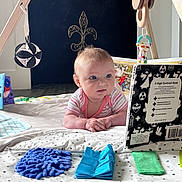 Isla joined the competition — help win amazing prizes! baby, infant, play_mat, high_contrast_book, wooden_baby_gym, hanging_toys, striped_clothing, floor, indoor, curious_expression, blue_eyes, fleur_de_lis, decor, soft_toys, child, person, early_learning, baby_playing, baby_toys, crawling