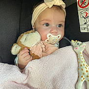 Ava participe au concours pour gagner de l'argent avec cette photo : baby, pacifier, headband, bow, plush_toy, blanket, car_seat, giraffe_toy, child, soft_texture, cute, infant, clothing, hand, face, portrait, indoor, comfort, toy, pink
