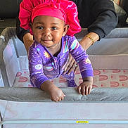 Nyla joined the competition — help win amazing prizes! adult, baby, bracelet, child, clothing, cute, earrings, floor, furniture, happy, home, indoor, person, pink_bonnet, playpen, purple_pajamas, smiling, standing, supporting_hand, woman