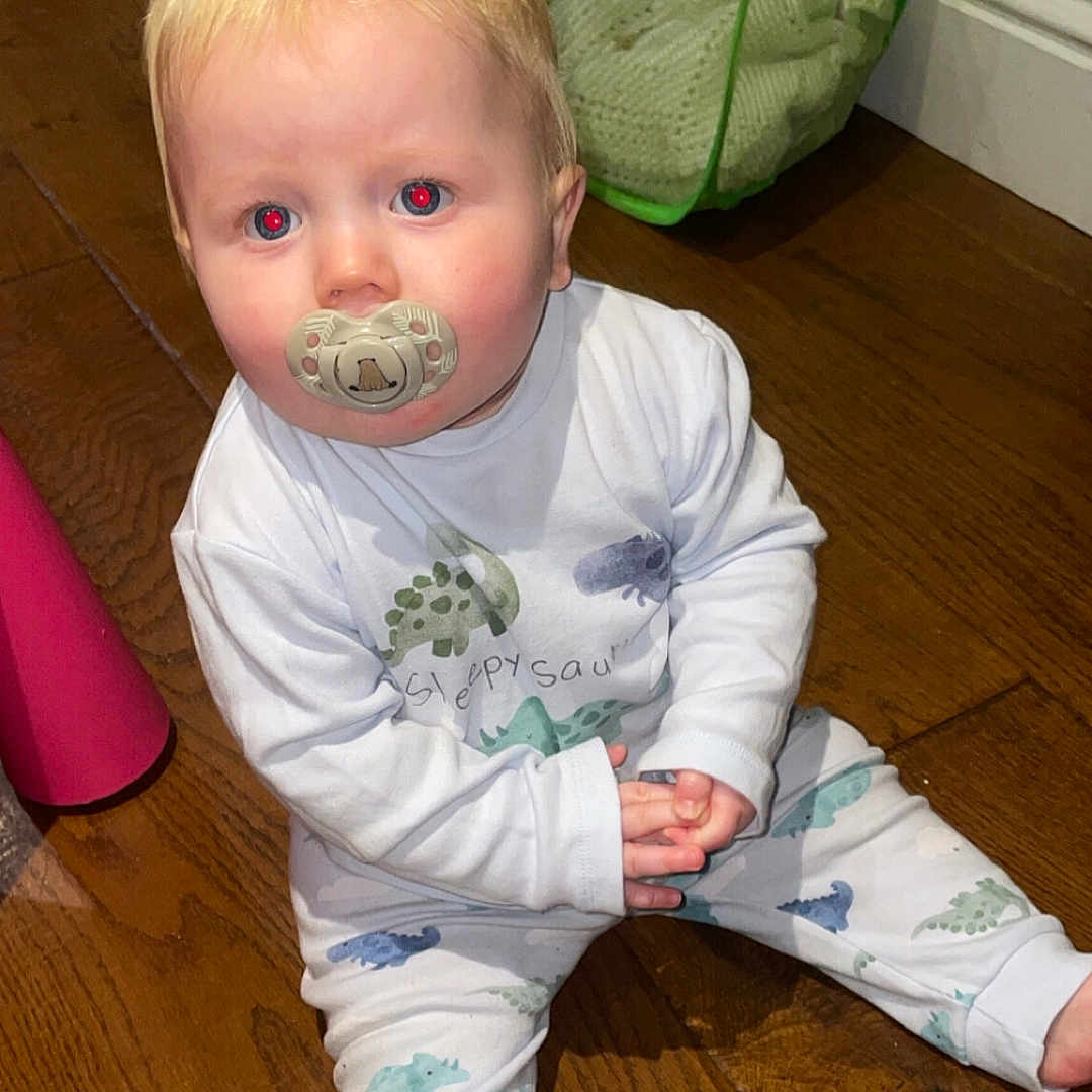 Cobie Lewis joined the competition — help win amazing prizes! baby, blond_hair, casual, child, clothing, curious, dinosaur_pattern, flooring, home, indoor, infant, laundry_basket, long_sleeve, pacifier, pajamas, pants, person, sitting, toddler, wooden_floor