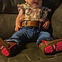 baby, boots, bow, casual, child, clothing, comfortable, couch, cute, denim_jeans, fashion, happy, headband, indoor, infant, person, plaid_shirt, portrait, sitting, smiling