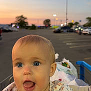 Ellie joined the competition — help win amazing prizes! baby, child, shopping_cart, tongue_out, blue_eyes, blonde_hair, sunset, parking_lot, bags, clothing, outdoor, person, streetlights, curious, cute, infant, face, expression, summer, shopping