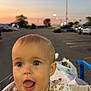 baby, child, shopping_cart, tongue_out, blue_eyes, blonde_hair, sunset, parking_lot, bags, clothing, outdoor, person, streetlights, curious, cute, infant, face, expression, summer, shopping