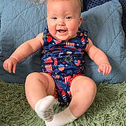 Emma joined the competition — help win amazing prizes! baby, child, smiling, onesie, sitting, indoor, pillow, rug, happy, face, cute, infant, legs, sock, blue, red, green, pattern, celebration, person