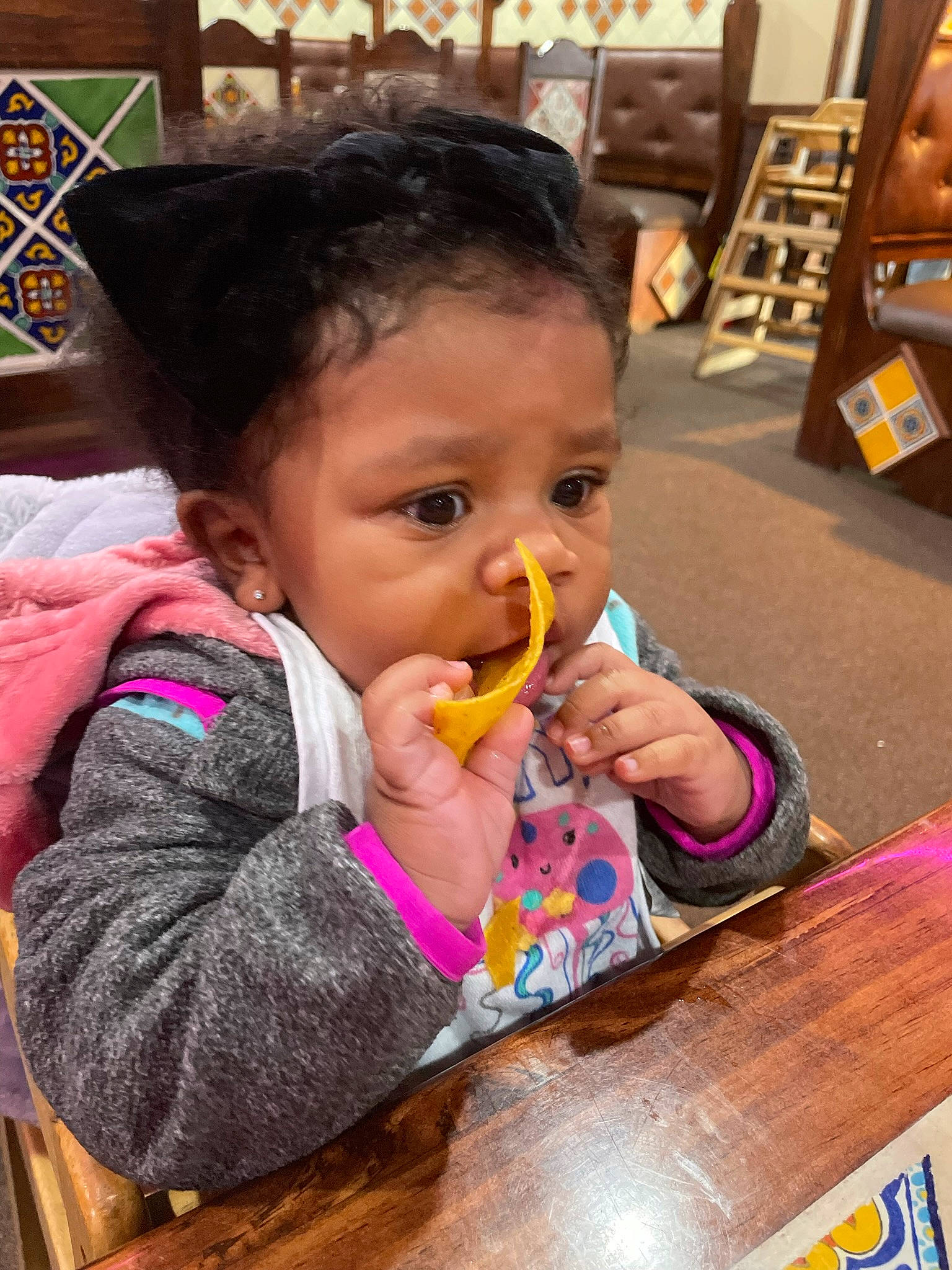 Demi is registered to the contest to win money with this photo: baby, baby_toddler_clothing, biting, chair, cheek, child, darts, finger, fun, happy, iris, mouth, nose, organ, person, sharing, skin, sweetness, table, tableware