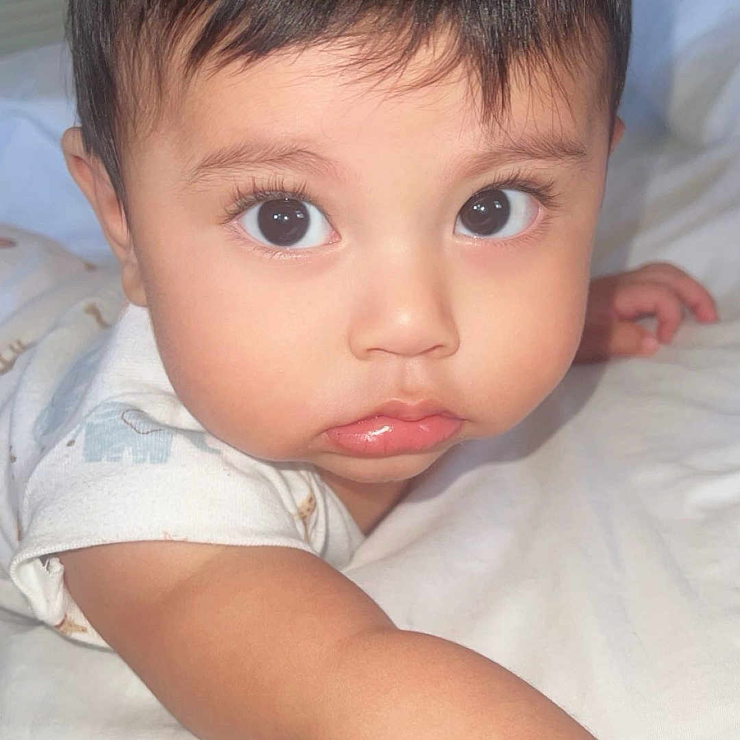 Christopher Ospina joined the competition — help win amazing prizes! arm, baby, bed, child, closeup, curious, cute, expression, eyes, face, indoors, infant, lying_down, person, portrait, skin, sleepwear, soft_light, white, young