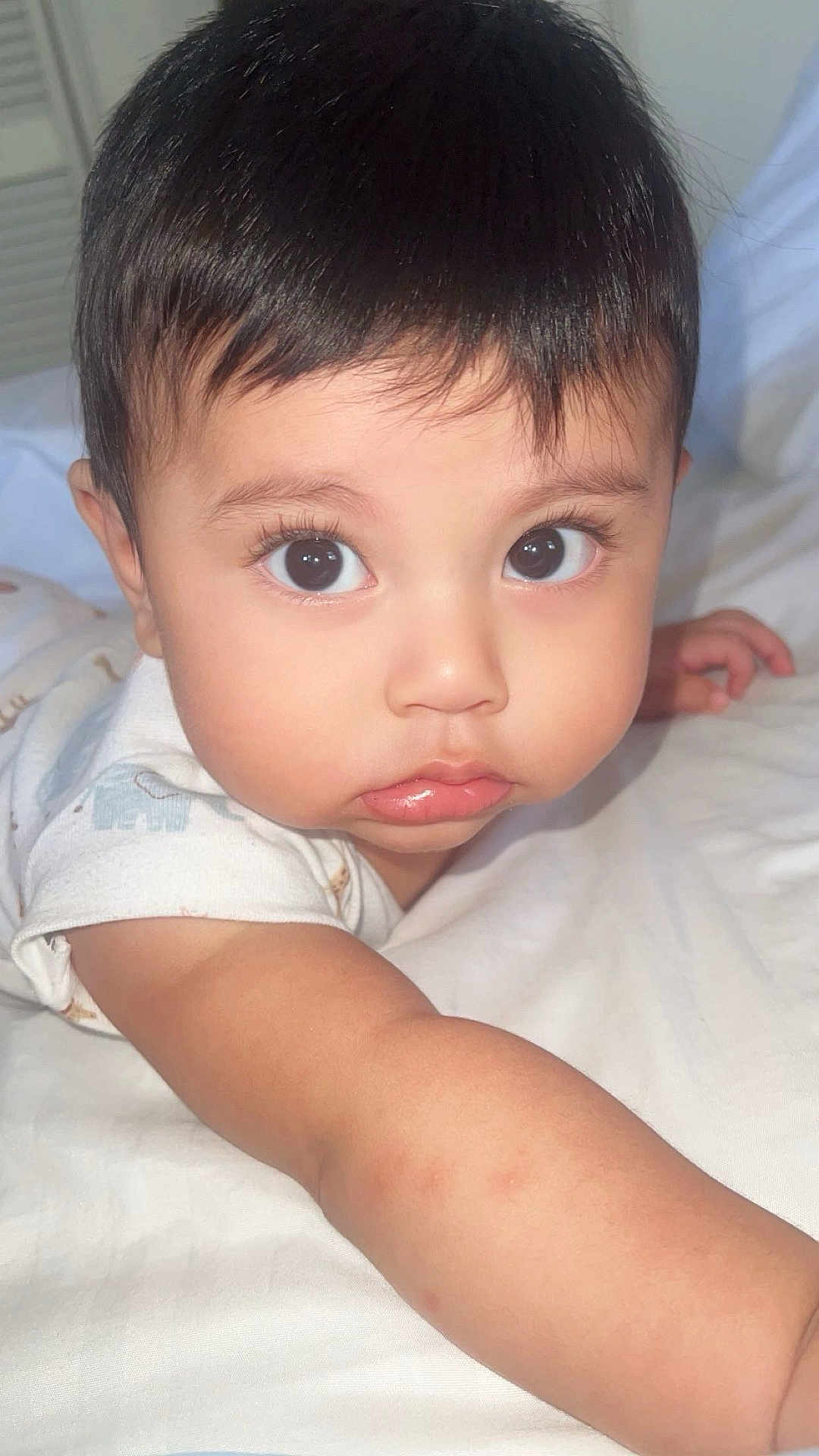 Christopher Ospina joined the competition — help win amazing prizes! baby, child, face, eyes, arm, skin, bed, white, closeup, curious, cute, infant, portrait, person, young, indoors, sleepwear, expression, soft_light, lying_down