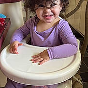 Adalina joined the competition — help win amazing prizes! toddler, child, smiling, high_chair, purple_clothing, curly_hair, indoor, kitchen, happy, person, furniture, table, face, long_sleeve, pants, princess_cartoon, seat, cute, young_child, playful