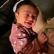 Adalina is registered to the contest to win money with this photo: baby, newborn, smiling, face, hand, tattoo, onesie, clothing, person, infant, cozy, sleepy, cute, indoor, portrait, human, comfort, love, care, skin