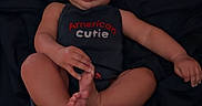 Freya is registered to the contest to win money with this photo: baby, baby_pose, blanket, child, clothing, cute, dark_background, expression, face, foot, hand, indoors, infant, lying_down, onesie, person, portrait, skin, tongue_out, young_child