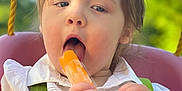 Ivy joined the competition — help win amazing prizes! toddler, child, popsicle, swing, outdoor, summer, greenery, happy, cute, playtime, food, snack, sunlight, daytime, seatbelt, white_shirt, hands, face, portrait, nature