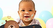 Kailani is registered to the contest to win money with this photo: baby, background, balloons, cake_crumbs, cartoon_bear, celebration, child, clothing, colorful, cute, face_paint, fun, happy, indoor, infant, pastel_colors, playful, portrait, smiling, text_overlay