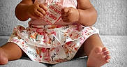 Ciara is registered to the contest to win money with this photo: baby, band_aid, child, clothing, couch, curious, cute, expression, floral_skirt, foot, girl, gray_couch, hand, headband, indoors, infant, pink_top, portrait, sitting, skin