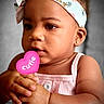 Ciara joined the competition — help win amazing prizes! baby, child, close_up, clothing, cute, earrings, expression, face, hands, headband, heart, holding, indoor, person, pink, portrait, sign, skin, soft_background, toddler