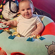 Dino participe au concours pour gagner de l'argent avec cette photo : baby, infant, smiling, cushion, colorful, indoor, sofa, television, foot, hand, clothing, toy, fabric, face, person, child, home, comfort, seat, playful