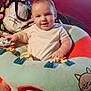 baby, infant, smiling, cushion, colorful, indoor, sofa, television, foot, hand, clothing, toy, fabric, face, person, child, home, comfort, seat, playful