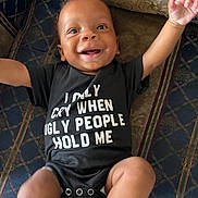 Legend is registered to the contest to win money with this photo: baby, infant, smile, happy, onesie, clothing, face, arms, couch, pattern, fabric, child, joy, portrait, indoor, person, cute, funny_text, expression, skin