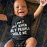 baby, infant, smile, happy, onesie, clothing, face, arms, couch, pattern, fabric, child, joy, portrait, indoor, person, cute, funny_text, expression, skin