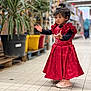 Faiha participe au concours pour gagner de l'argent avec cette photo : child, red_dress, sneakers, store, aisle, plants, pots, tiles, curly_hair, standing, indoor, shopping, person, cute, young, expression, floor, blurred_background, casual, fashion