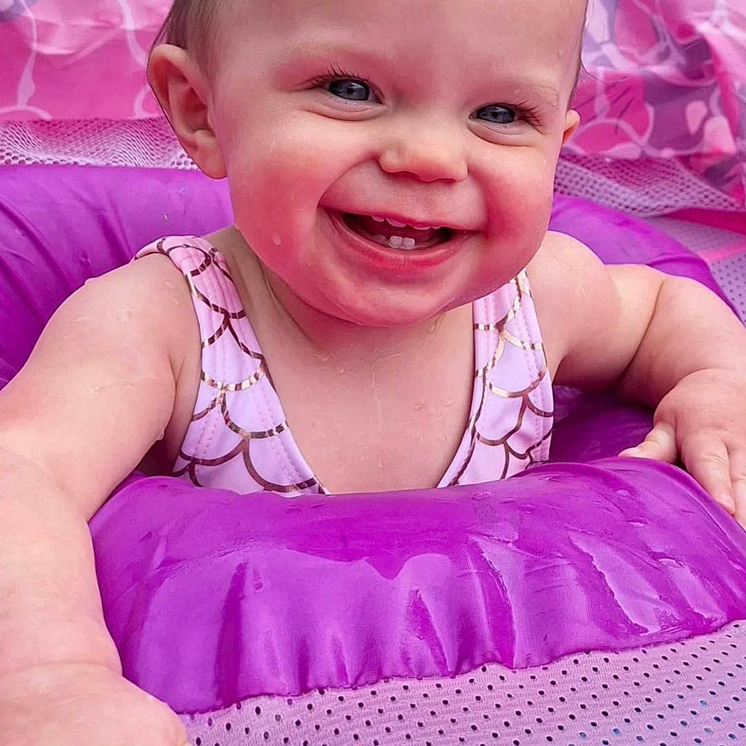 Ramona is registered to the contest to win money with this photo: baby, child, cute, face, fun, hand, happy, inflatable, outdoor, pink, play, pool, purple, skin, smiling, splashing, summer, swimsuit, tooth, water