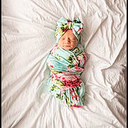 Georgia joined the competition — help win amazing prizes! newborn, baby, swaddled, blanket, bow, headband, floral_pattern, sleeping, white_sheet, bed, cozy, infant, cute, resting, portrait, soft_lighting, wrapped, peaceful, child, indoors