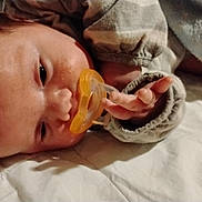 Noble is registered to the contest to win money with this photo: baby, pacifier, infant, sleeping, blanket, clothing, hand, face, skin, closeup, lying_down, indoors, cozy, soft, child, newborn, cute, young, peaceful, resting