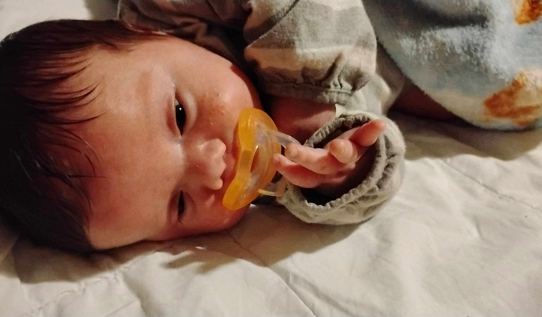 Noble is registered to the contest to win money with this photo: baby, pacifier, infant, sleeping, blanket, clothing, hand, face, skin, closeup, lying_down, indoors, cozy, soft, child, newborn, cute, young, peaceful, resting