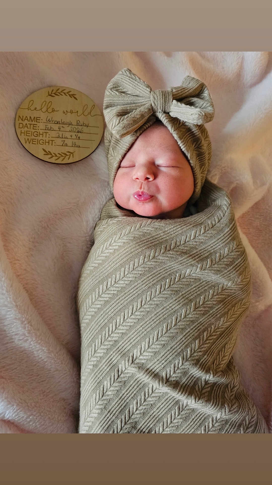 Wrenleigh is registered to the contest to win money with this photo: newborn, baby, swaddled, bow_headband, blanket, wooden_disc, milestone_disc, puckered_lips, sleeping, portrait, cozy, soft_texture, fabric_pattern, face, head, skin, indoor, cute, laying, neutral_tones