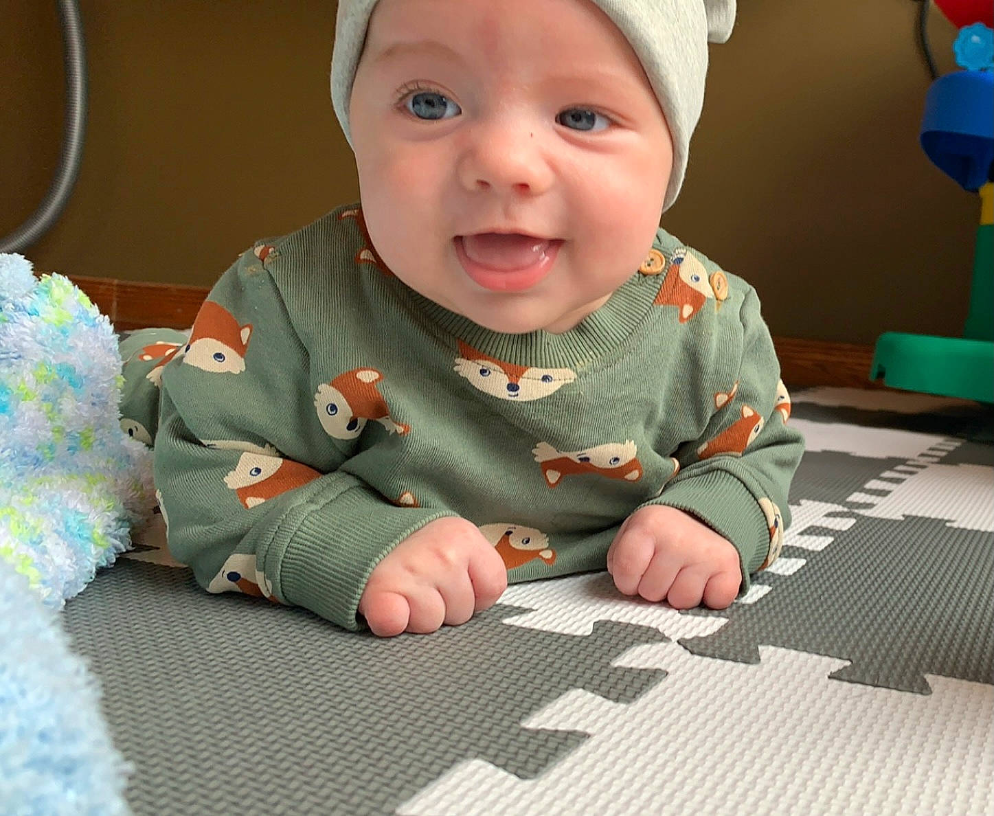 Donovan a rejoint le concours — aidez-le/la à gagner de superbes lots ! baby, baby_products, baby_toddler_clothing, cheek, child, face, facial_expression, finger, flooring, fun, green, happy, head, headwear, person, sitting, skin, sleeve, smile, textile