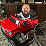 Stephen is registered to the contest to win money with this photo: baby, bib, cabinet, car_seat, car_toy, carpet, child, decor, floor, furniture, happy, indoor, living_room, person, photograph, play, red, smiling, sock, toy_car