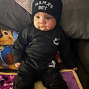 Stephen joined the competition — help win amazing prizes! baby, child, black_clothing, beanie, hat, sitting, quilt, pillow, paw_patrol, indoors, cute, chubby_cheeks, face, person, clothing, blanket, expression, portrait, young_child, casual