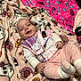 Cheyenne joined the competition — help win amazing prizes! baby, smiling, headband, plush_toy, blanket, patterned_blanket, pink_clothing, bib, white_socks, infant, cute, happy, child, indoor, soft_texture, toy, person, cozy, lying_down, colorful