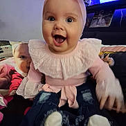Cheyenne is registered to the contest to win money with this photo: baby, infant, smiling, open_mouth, headband, bow, pink_clothing, ruffles, jeans, socks, sitting, pillow, couch, lamp, photograph, home_interior, portrait, cute, happy, eyes